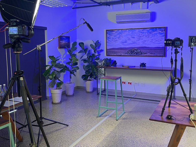 The interview set, with lighting, cameras and a framed landscape backdrop.