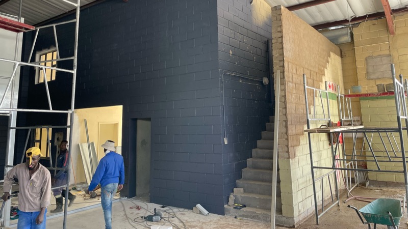 Interior construction with a new dark block wall and a refurbished staircase.