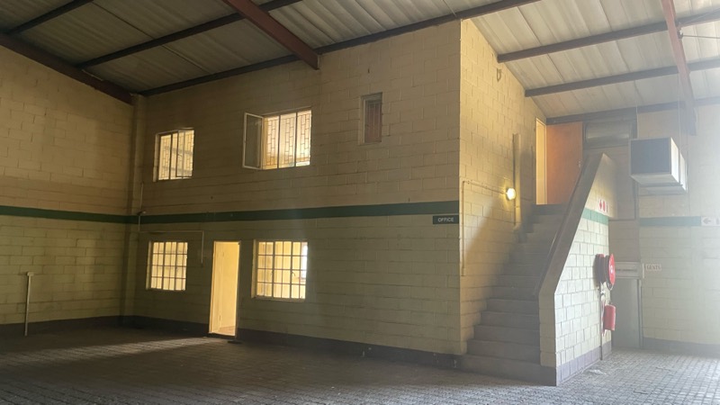 A double-height interior with barred windows and a staircase against the far wall.