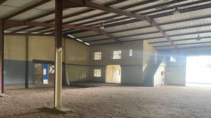 The cleared warehouse interior with a sand floor and daylight from the open end.