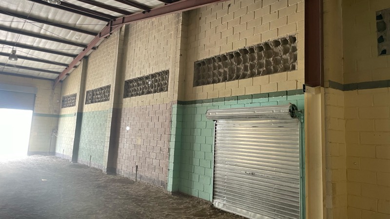 The interior beside a closed roller shutter opening in the block wall.