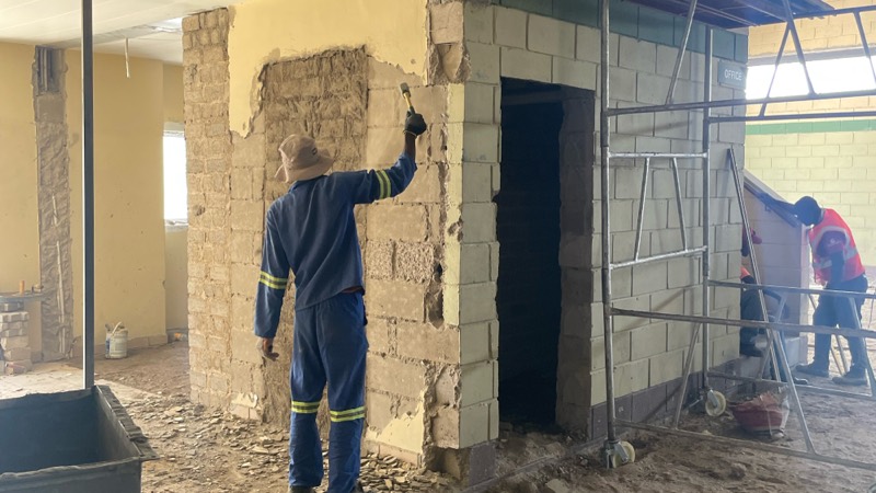 A worker plastering a new opening cut into an internal wall.