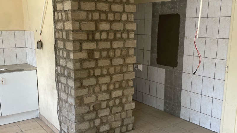 A stripped tiled room with a new brick column and openings prepared.