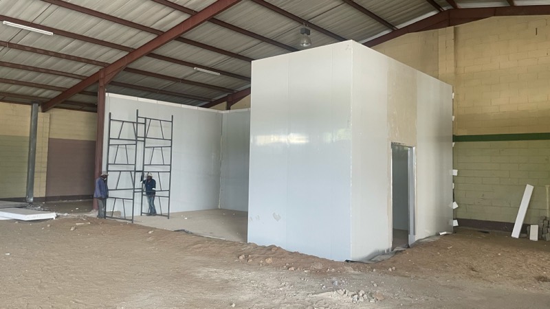 The white cold-room structure partly built inside the warehouse, with scaffolding alongside.
