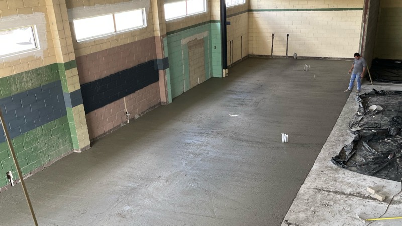 The finished floor slab in the retail area, with a worker at the far wall.