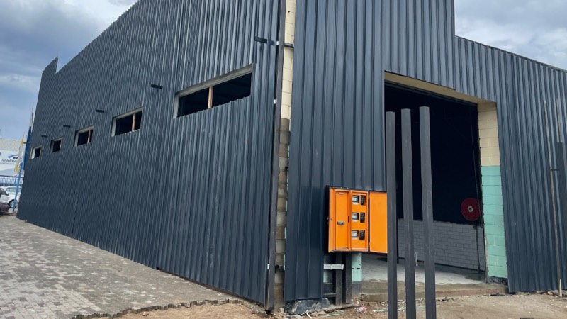 The fully clad dark facade with new window openings and a roller door.