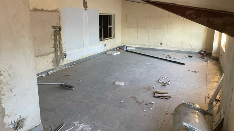A stripped upper room with debris on the floor, ready for finishing.